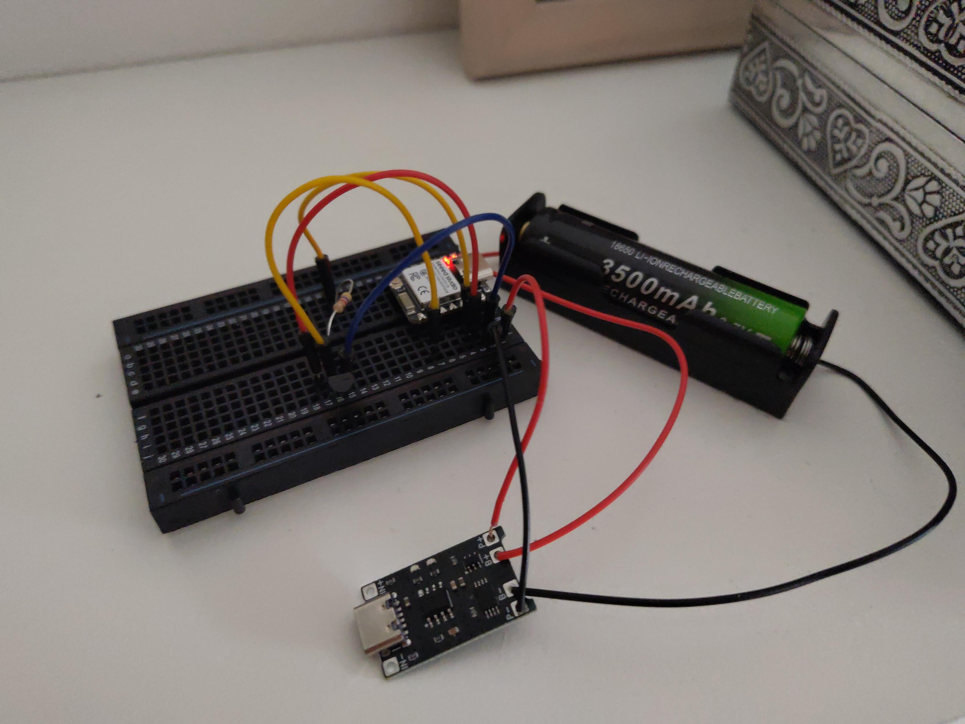 Ein ESP32 ist mit mehreren Kabeln, elektronischen Bauteilen auf einem Steckbrett befestigt und mit einem Batteriepack mit 3500mAh Kapazität verbunden. Im Hintergrund sind Teile einer Metallschachtel zu sehen.